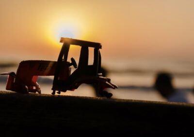 tractor, juguete, silueta, puesta de sol, atardecer, naranja, contraluz, miniatura, campo, agricultura, sol, horizonte, luz cálida, nostalgia, escena creativa, sombra, composición artística, exterior, calma, fotografía conceptual.