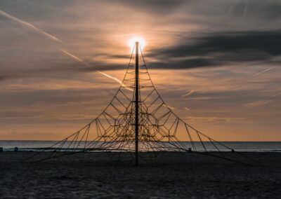 playa, cuerdas, estructura, red, atardecer, sol, mar, silueta, contraluz, cielo naranja, juegos, arena, costa, paisaje marino, horizonte, composición simétrica, luz cálida, tranquilidad, fotografía artística, verano
