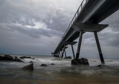pasarela, mar, costa, rocas, agua, larga exposición, nubes, tormenta, cielo gris, paisaje marino, litoral, olas, espuma, horizonte, dramatismo, estructura, puente, playa, atmósfera, naturaleza, fotografía de paisaje, movimiento, agua sedosa, temporal, contraste.