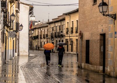 lluvia, paraguas, calle histórica, adoquines, reflejos, arquitectura tradicional, paseo, casco antiguo, día lluvioso, escena urbana, pueblo, turismo, farolas, calles mojadas, España.