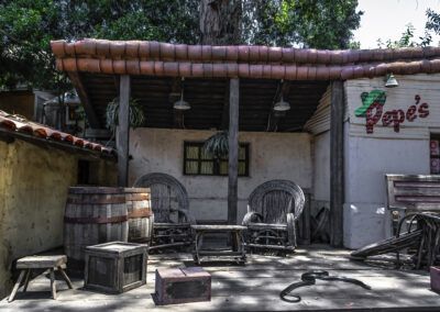 viejo oeste, western, decorado, escenario rústico, barriles, madera, mecedoras, serpiente, cantina, pueblo del oeste, parque temático, ambientación, aventura, mobiliario antiguo, escena cinematográfica.