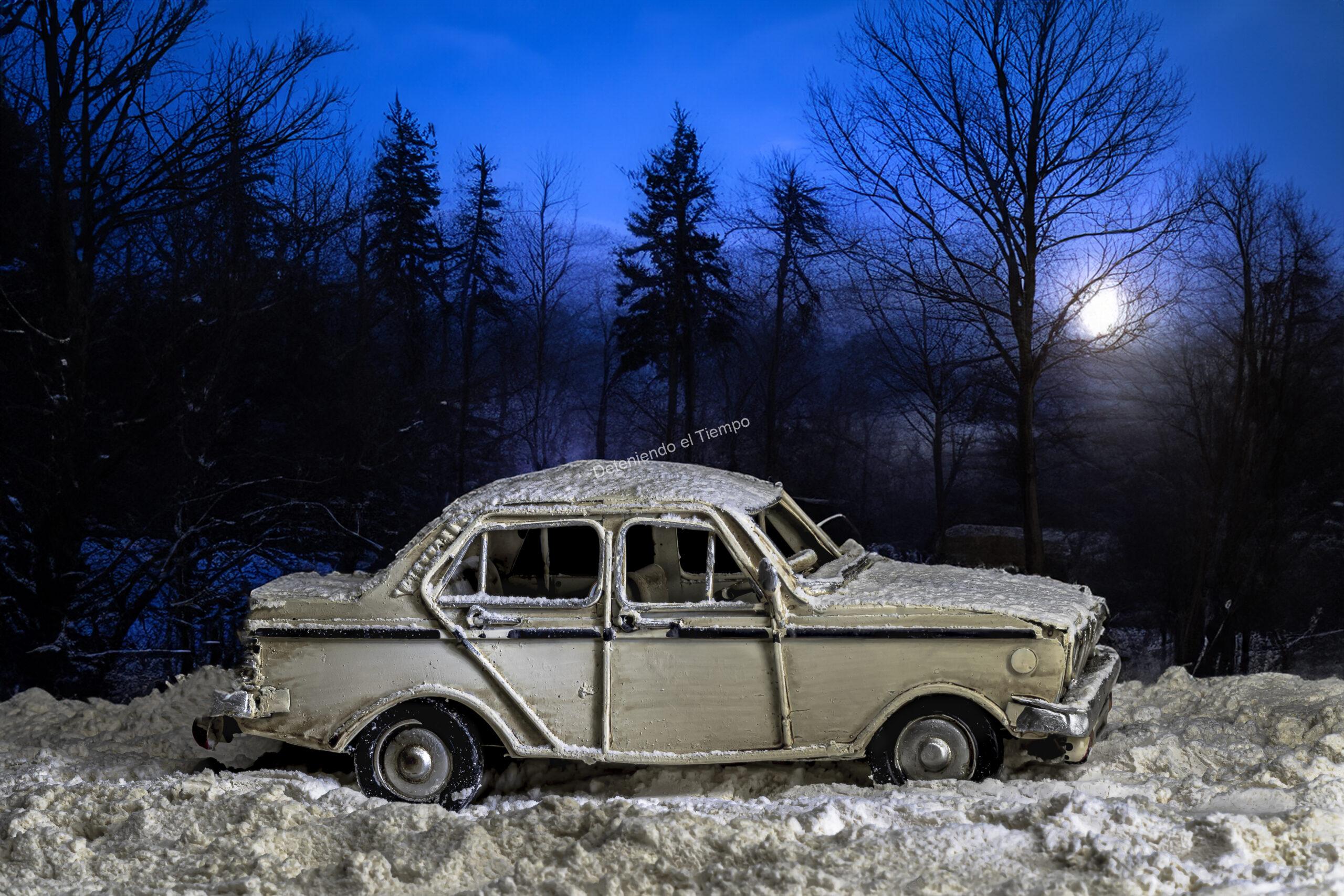 Vehículo cubierto por nieve bajo la luz de la luna, inmerso en un paisaje invernal silencioso. La escena transmite soledad, abandono y el paso del tiempo en un entorno natural dominado por tonos fríos y una atmósfera cinematográfica.