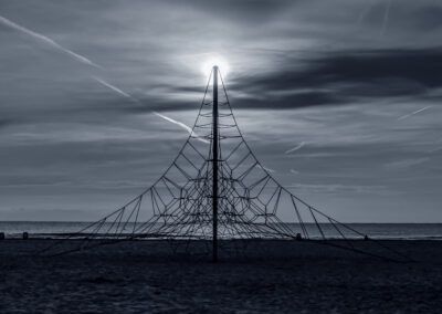 playa, mar, estructura de cuerdas, silueta, sol, contraluz, geometría, simetría, cielo, costa, horizonte, parque infantil, red de escalada, minimalismo, tranquilidad, paisaje marino, composición, luz solar, arena, fotografía artística.