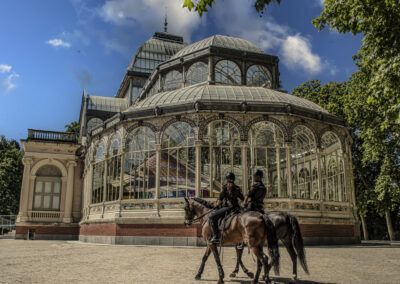 Palacio de Cristal, parque del Retiro, Madrid, policía a caballo, caballos, agentes, arquitectura de hierro, cristal, patrimonio, parque urbano, seguridad, turismo, monumento, naturaleza, España.