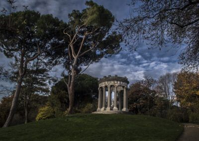 templete, arquitectura clásica, monumento, columnas, jardín histórico, parque, naturaleza, árboles, pinos, otoño, cielo dramático, nubes, paisaje, patrimonio, escultura, vegetación, Madrid, Parque del Capricho, romanticismo, tranquilidad.