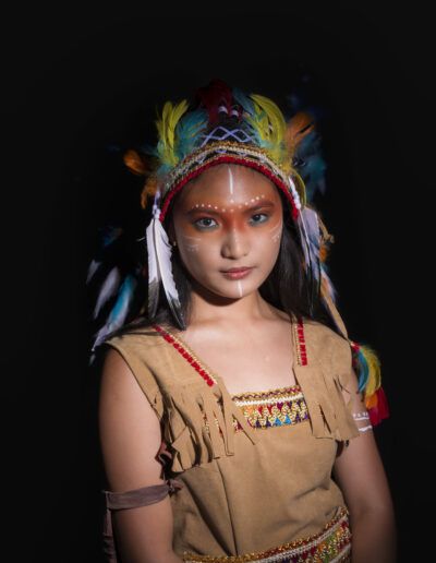 joven, retrato, tocado, plumas, fondo negro, luz frontal, maquillaje artístico, vestuario fantástico, pose, estudio, colores, expresión, fotografía creativa, personaje, moda.