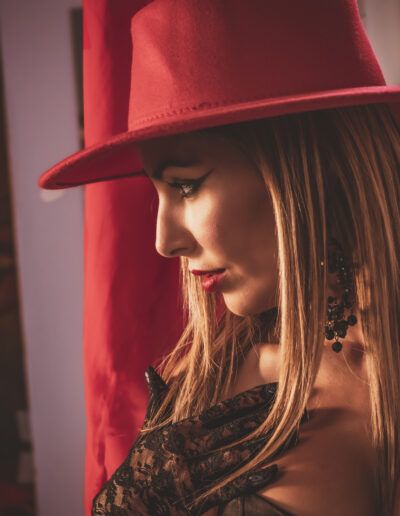perfil, mujer, sombrero rojo, guantes negros, encaje, luz cálida, retrato, moda, labios rojos, elegancia, glamour, iluminación dramática, fotografía artística, estilo, feminidad.