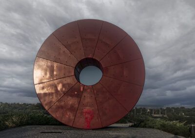 escultura, círculo rojo, arte contemporáneo, monumento, parque, cielo nublado, geometría, paisaje, instalación artística, forma circular, contraste, espacio público, perspectiva frontal, arquitectura moderna, Madrid.