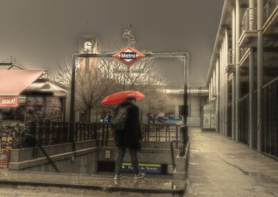 Puerta de Toledo, Metro de Madrid, lluvia, paraguas rojo, persona, estación de metro, escena urbana, Madrid, día gris, transporte público, soledad, calle mojada, invierno, ciudad, vida cotidiana.