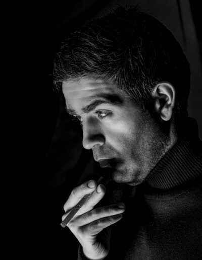hombre, retrato, blanco y negro, cigarro, pensamiento, concentración, mirada, iluminación lateral, fondo negro, expresión, masculinidad, primer plano, dramatismo, introspección, fotografía de estudio.