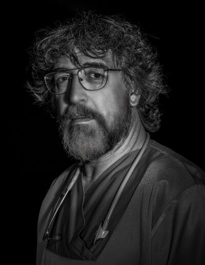 médico, retrato profesional, estetoscopio, gafas, barba, blanco y negro, salud, medicina, hospital, sanitario, mirada, primer plano, confianza, profesionalidad, fondo negro.