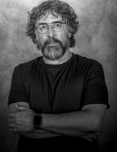 hombre, retrato, barba, gafas, brazos cruzados, blanco y negro, camiseta negra, fondo texturizado, personalidad, seriedad, fotografía de estudio, mirada frontal, madurez, carácter, retrato masculino.