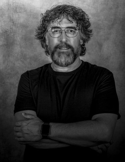 hombre, retrato masculino, barba, gafas, blanco y negro, brazos cruzados, serenidad, fondo gris, expresión, fotografía de estudio, madurez, mirada, confianza, personalidad, pose.
