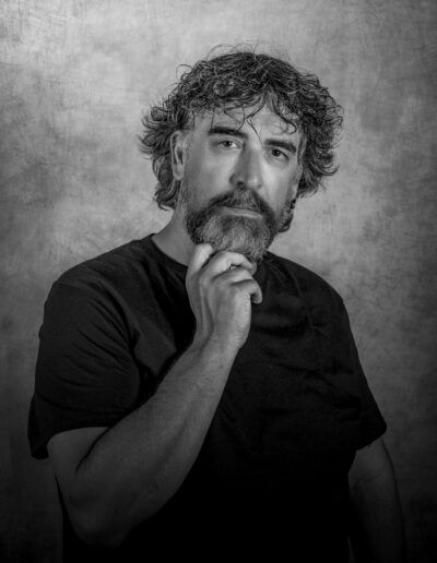 hombre, retrato, barba, reflexión, blanco y negro, mano en la barbilla, serenidad, mirada frontal, fondo gris, pensamiento, fotografía de estudio, madurez, expresión, contemplación, retrato masculino.